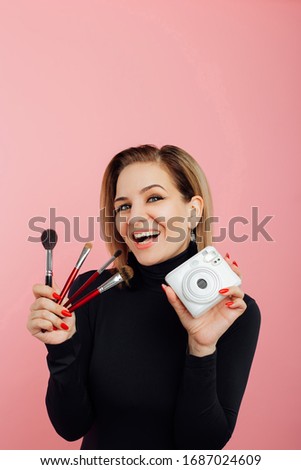 girl on a pink background with a camera and makeup brushes.Pin up woman looking through paper. copy space.Breaking paper. Sale. Discount