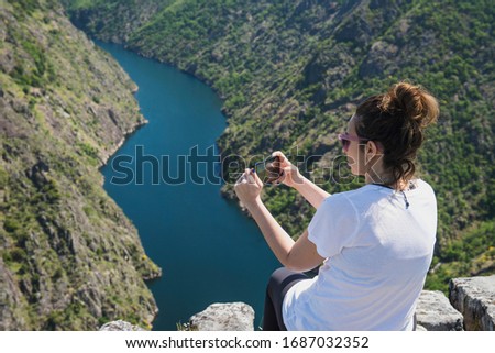 Woman taking pictures with her smartphone in a beautiful viewpoint in the Sil Canyon. Ribeira Sacra, Galicia
