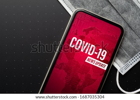 Coronavirus or Covid-19 outbreak News Update background concept. Mockup mobile phone Coronavirus News with facial masks. Flat lay top view with copy space. Royalty-Free Stock Photo #1687035304