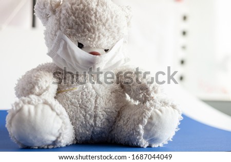 Teddy bear in a medical mask on a white and blue background. Respiratory medicine.
