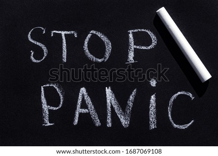 Drawing with chalk on a black blackboard, handwritten text Stop Panic.