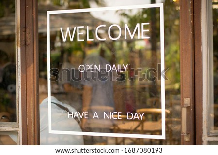 Label welcome open daily have a nice day on the door at coffee shop.