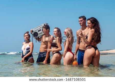 Beautiful women in bikinis and male athletes having fun on the beach
