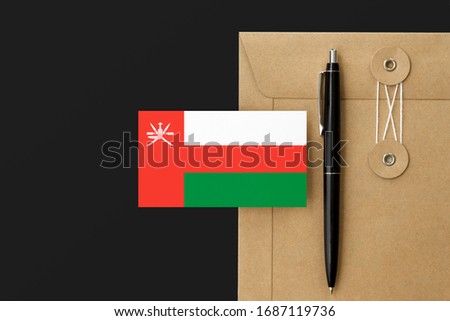 Oman flag on craft envelope letter and black pen background. National invitation concept. Invitation for education theme.