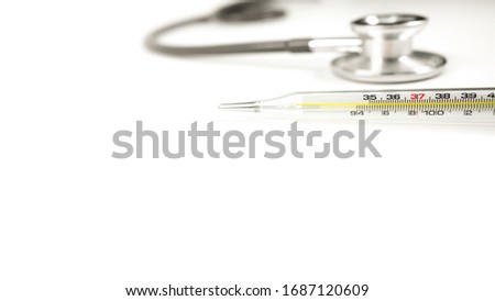 Glass bulb thermometer for human body temperature Placed in the top right corner of the picture, near the doctor's headphones, placed horizontally, with copy space on the left on a white background