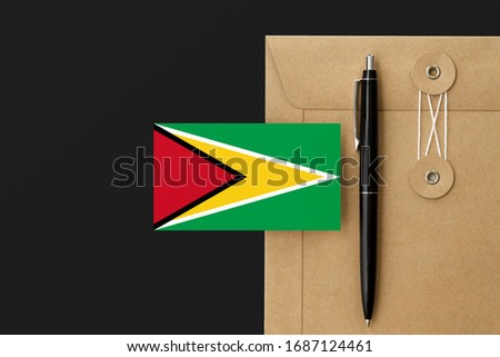 Guyana flag on craft envelope letter and black pen background. National invitation concept. Invitation for education theme.
