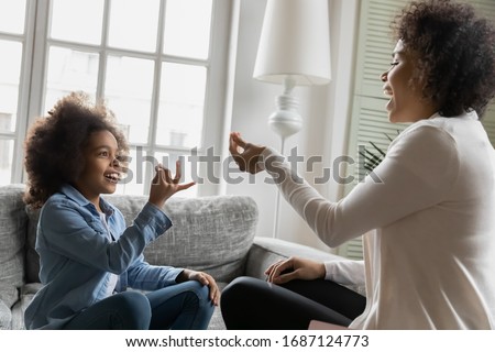 African disabled daughter and her mother sitting on sofa show symbols with hands using visual-manual finger gestures interacting at home. Hearing loss deaf person sign language learning school concept Royalty-Free Stock Photo #1687124773