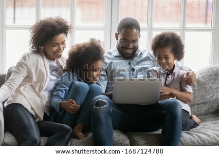 African couple and kids look at pc screen engaged at search of best offer travel full family trip, booking hotels use websites services buy on-line, make videocall, surfing web, watch cartoons concept