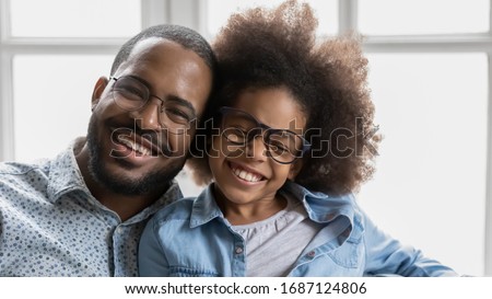 Close up image portrait of cheerful african father and little daughter with wide toothy healthy white smile wearing trendy stylish eyeglasses, advertise dental services or eyewear store offer concept Royalty-Free Stock Photo #1687124806