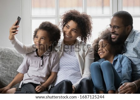 African ethnicity full family enjoy free time together relaxing on couch using smart phone new cool app, taking selfie picture capture moment or having distant communication making video call concept