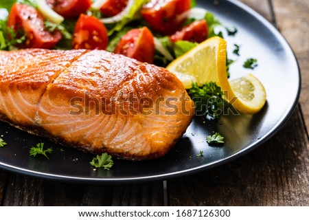 Fried salmon steaks with vegetables on wooden table Royalty-Free Stock Photo #1687126300