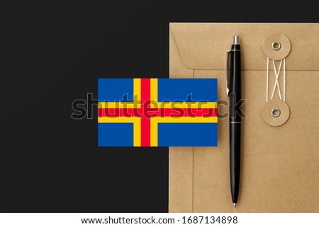 Aland Islands flag on craft envelope letter and black pen background. National invitation concept. Invitation for education theme.
