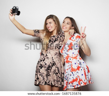 beautiful young women in summer dresses are photographed on a vintage camera, white background