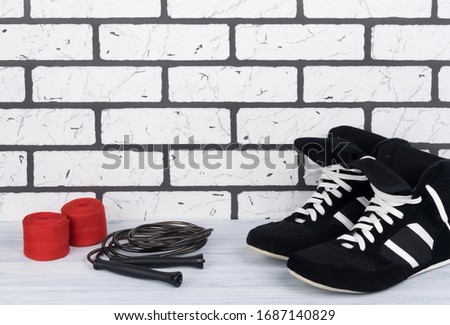 wrestling shoes, protective bandages and jumpers, concept on brick white wall background