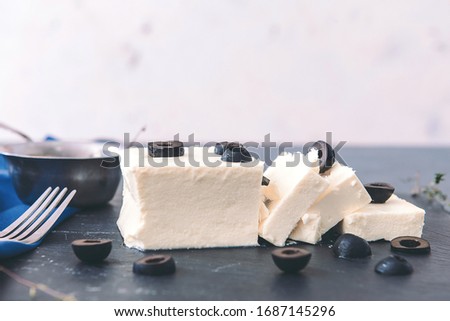 Tasty feta cheese with olives on table