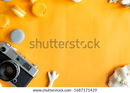 Top view of tasty orange yellow macarons and camera. Concepts ideas background on yellow paper, flatlay and copy Space