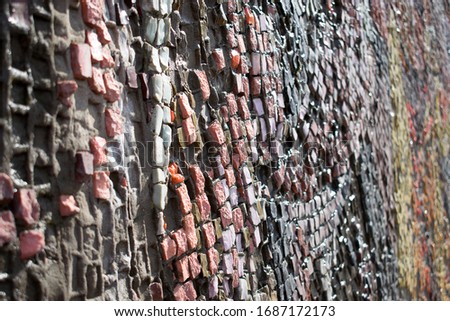 A fragment of a wall with a multicolored mosaic that goes into perspective.Abstract texture,creative background.Selective focus,blurred background.Copy space for text
