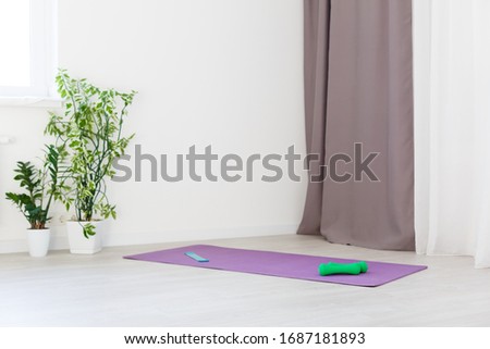 Unrolled yoga mat on wooden floor in modern fitness center or at home with big windows and white brick walls, comfortable space for doing sport exercises, meditating, yoga equipment Royalty-Free Stock Photo #1687181893