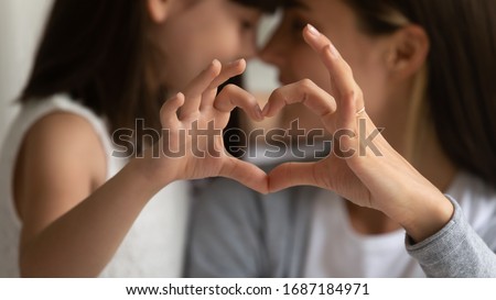 Close up of young mother and cute little daughter make heart sign with hands enjoy close tender moment together, caring mom and grateful small girl child show love and support in family relationships Royalty-Free Stock Photo #1687184971