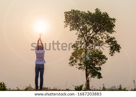 Christian, Christianity, Religion copy space background.Human praying and holding christian cross for worshipping God at sunset background.