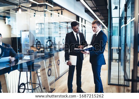 African American manager in business clothing falling in employee at modern office and pointing out inaccuracies in documents by request   Royalty-Free Stock Photo #1687215262