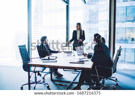 Confident male and female directors dressed discussing productive strategy during brainstorming at desktop with laptop computer with blank screen area for advertising text or financial website Royalty-Free Stock Photo #1687216375