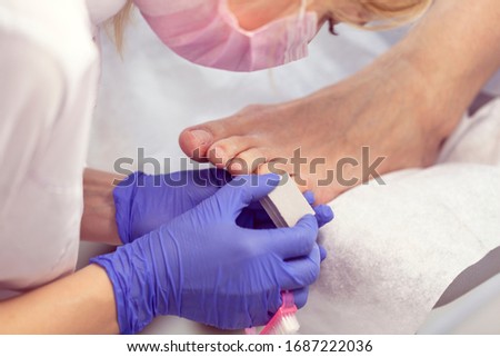 Close-up nail care by a pedicure specialist in a beauty salon. Pedicure transparent cuticle professional scissors for pedicure.