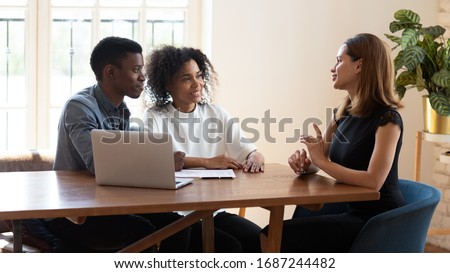 Female broker makes offer to young African ethnicity married couple during meeting in company office. Family taking loan in bank, listening advisor, real estate agent and customers negotiating concept Royalty-Free Stock Photo #1687244482