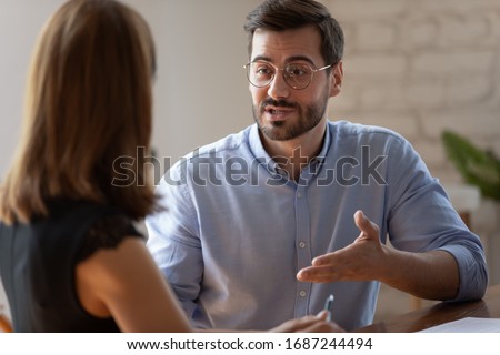 Caucasian male applicant answers on questions to HR female manager during job interview in office. Meeting process, negotiations communications between business parties, solutions and opinion concept Royalty-Free Stock Photo #1687244494