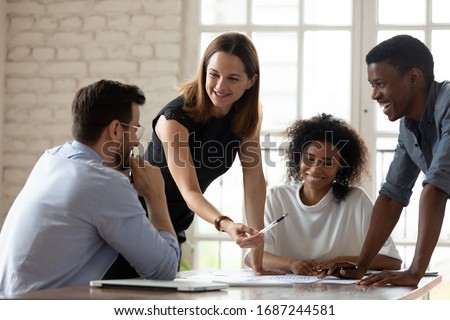 Caucasian woman team leader mentor teach staff multiethnic workers at corporate group briefing explain work results analyzing financial report together, planning project, brainstorming process concept Royalty-Free Stock Photo #1687244581