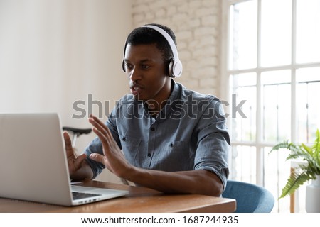 Serious confident African manager wear headphones looking at laptop screen talking provide support to client distantly, convincing customer buy company services. Student and e-learning process concept Royalty-Free Stock Photo #1687244935
