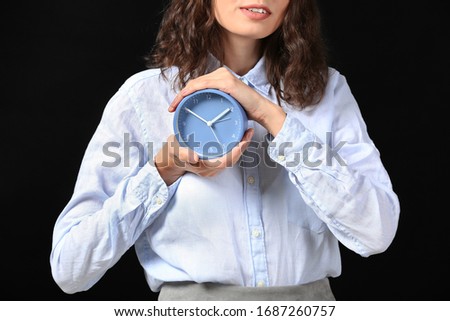 Businesswoman with alarm clock on dark background. Time management concept