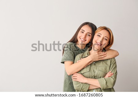 Portrait of young woman and mother on grey background Royalty-Free Stock Photo #1687260805