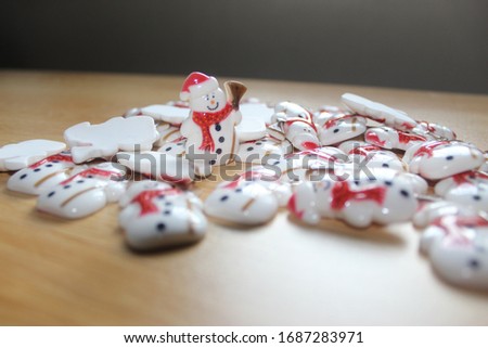 Many snowman laying on the wood floor with a red hat, red scarf. Standing with a broom with four black buttons, the face is full of smiles.
