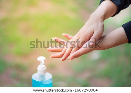 Female hands using wash hand sanitizer gel pump dispenser.

