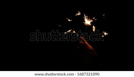 Abstract blur sparklers for celebration background,Motion by wind blurred hand holding burning Christmas sparkle on dark background.