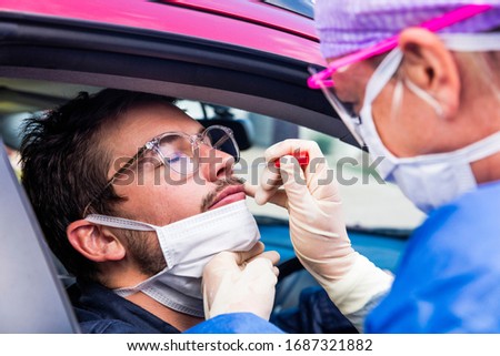 A doctor in a protective suit taking a nasal swab from a person to test for possible coronavirus infection Royalty-Free Stock Photo #1687321882