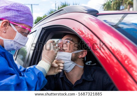 A doctor in a protective suit taking a nasal swab from a person to test for possible coronavirus infection Royalty-Free Stock Photo #1687321885