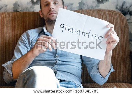 young man with a serious face shows a quarantine sign, home isolation during a pandemic, coronovirus covid -19