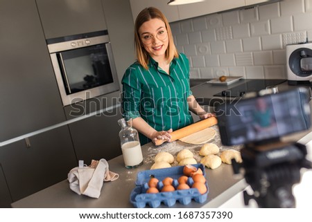 Young woman recording vlog at home in kitchen making croissants.