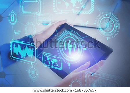 Hands of businesswoman working with tablet at blurry office table with double exposure of futuristic business infographics interface. Concept of hi tech. Toned image