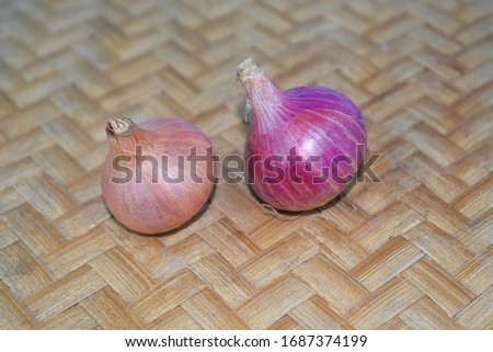 Two medium pieces of fresh red onion placed over a wood colored carpet background
