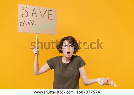 Shocked young protesting woman girl hold protest sign broadsheet placard on stick plastic bottle isolated on yellow background. Stop nature garbage ecology environment protection concept. Save planet