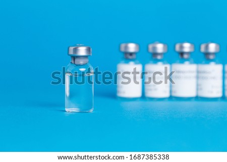 Closeup vaccine bottle on blue isolated background. Lack of coronovirus vaccine.