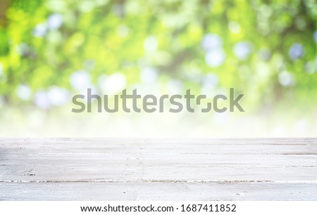 Empty white wooden table and blurred green nature background. Natural template with beauty bokeh and warm sunlight. Concept banner for products display 