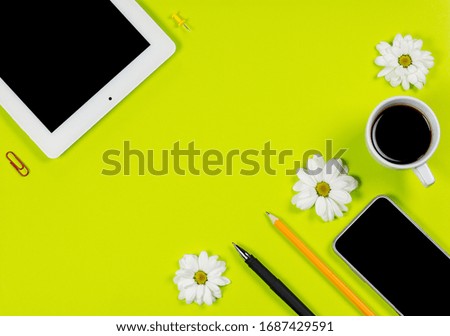 Various stationery and tablet with a phone for work and study and a cup of coffee on a green background