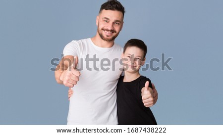 Like. Dad and son showing thumb up gesture, grey studio background