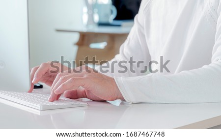 Cropped shot of man hand typing on white computer keyboard while working at home, working form home concept.