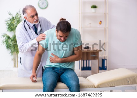 Injured young man visiting old doctor Royalty-Free Stock Photo #1687469395
