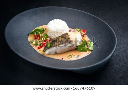 Gourmet fried skrei cod fish Thai curry with jasmine rice and chili as closeup on a modern design plate with copy space 